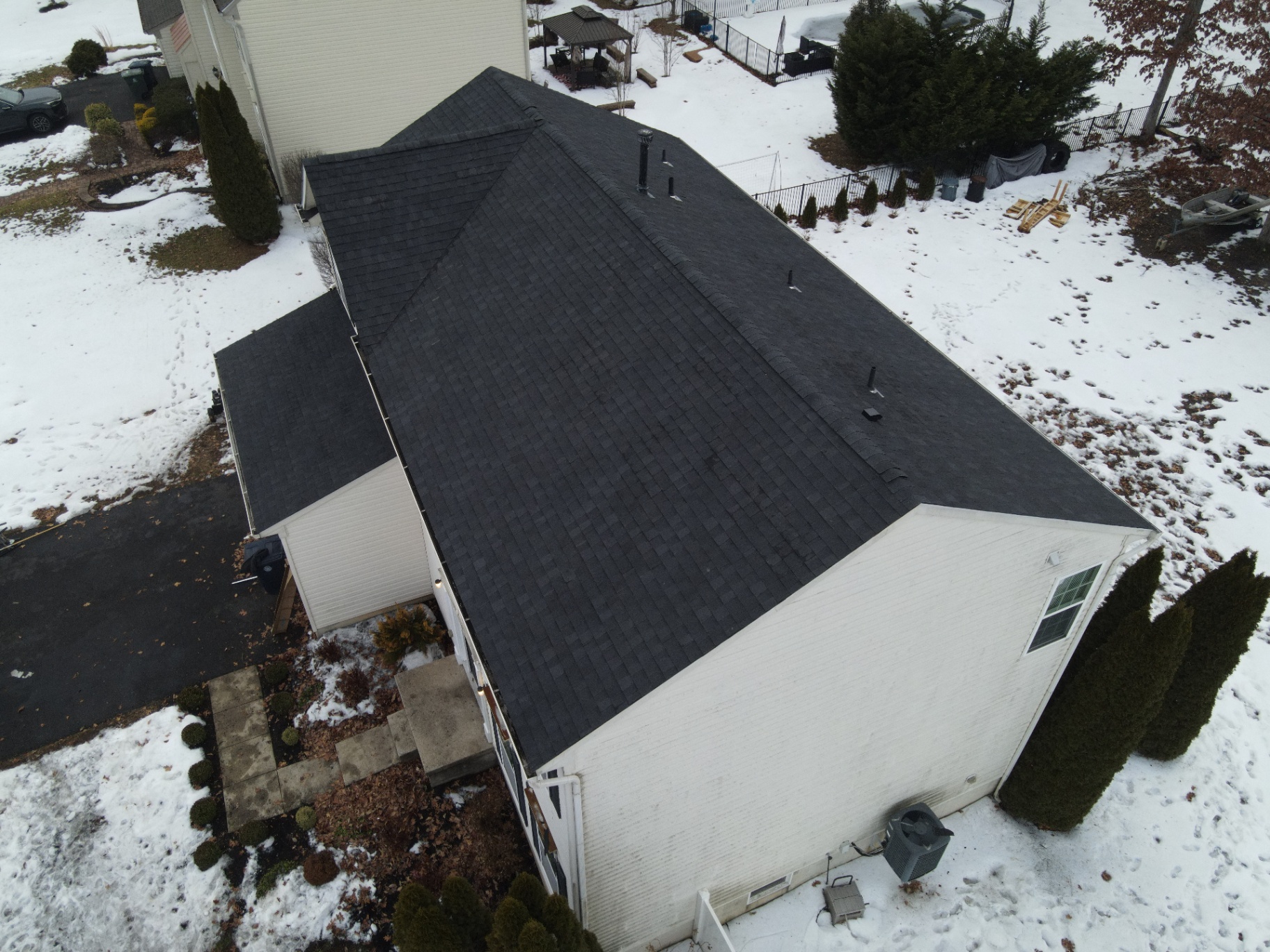 Completed black shingle roof on a two-story home in winter conditions