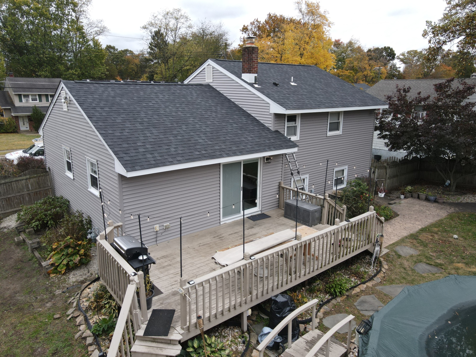 Rear elevation of a home with light gray vinyl siding and new architectural roof