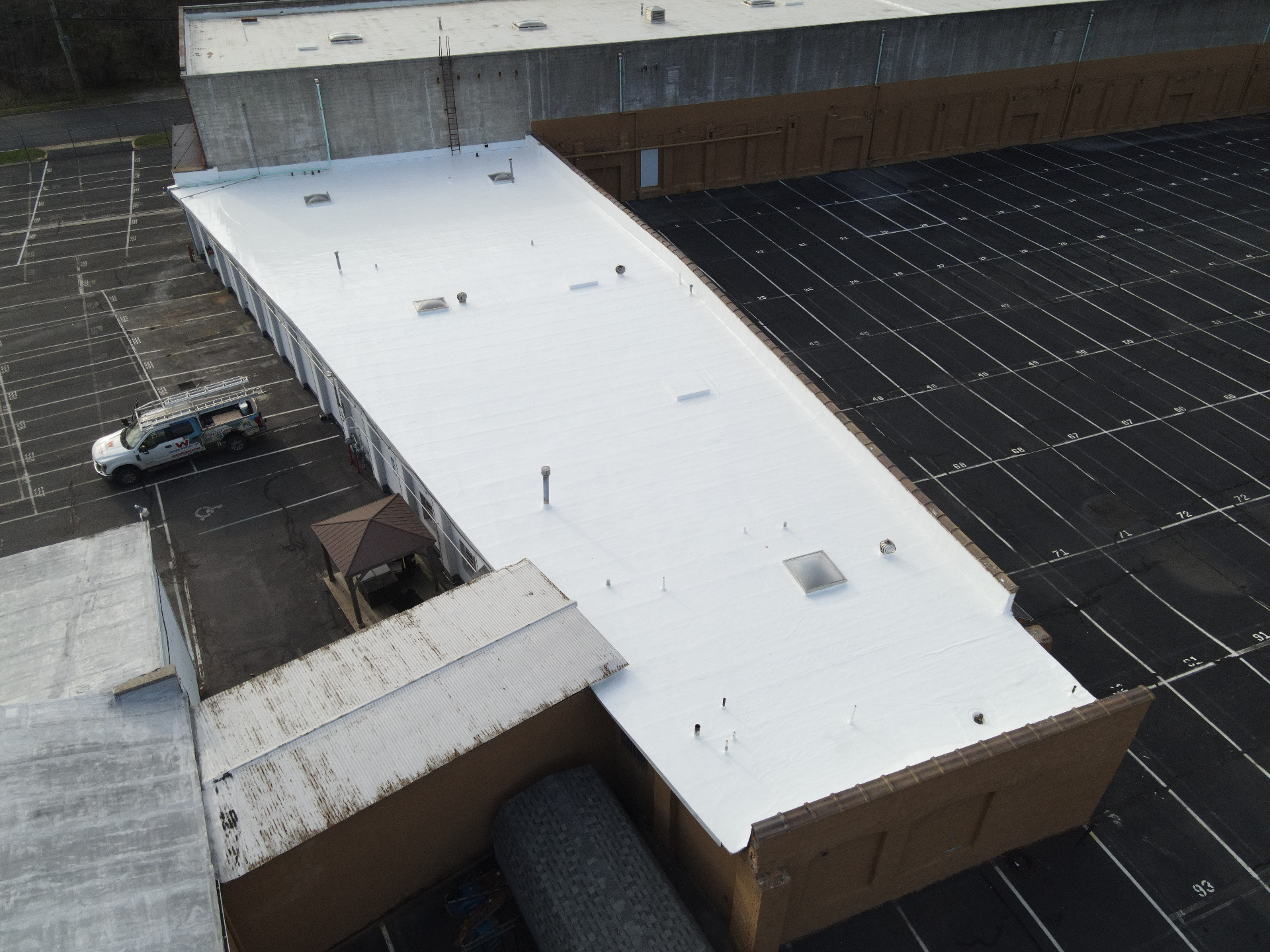 Finished white commercial flat roof from an overhead angle showing skylights and vents