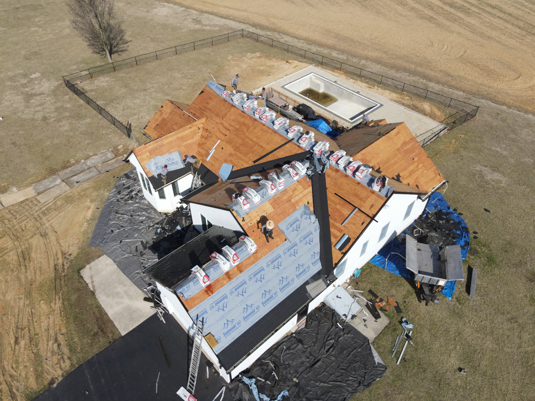 Crew working through a full tear-off on a large custom home roof