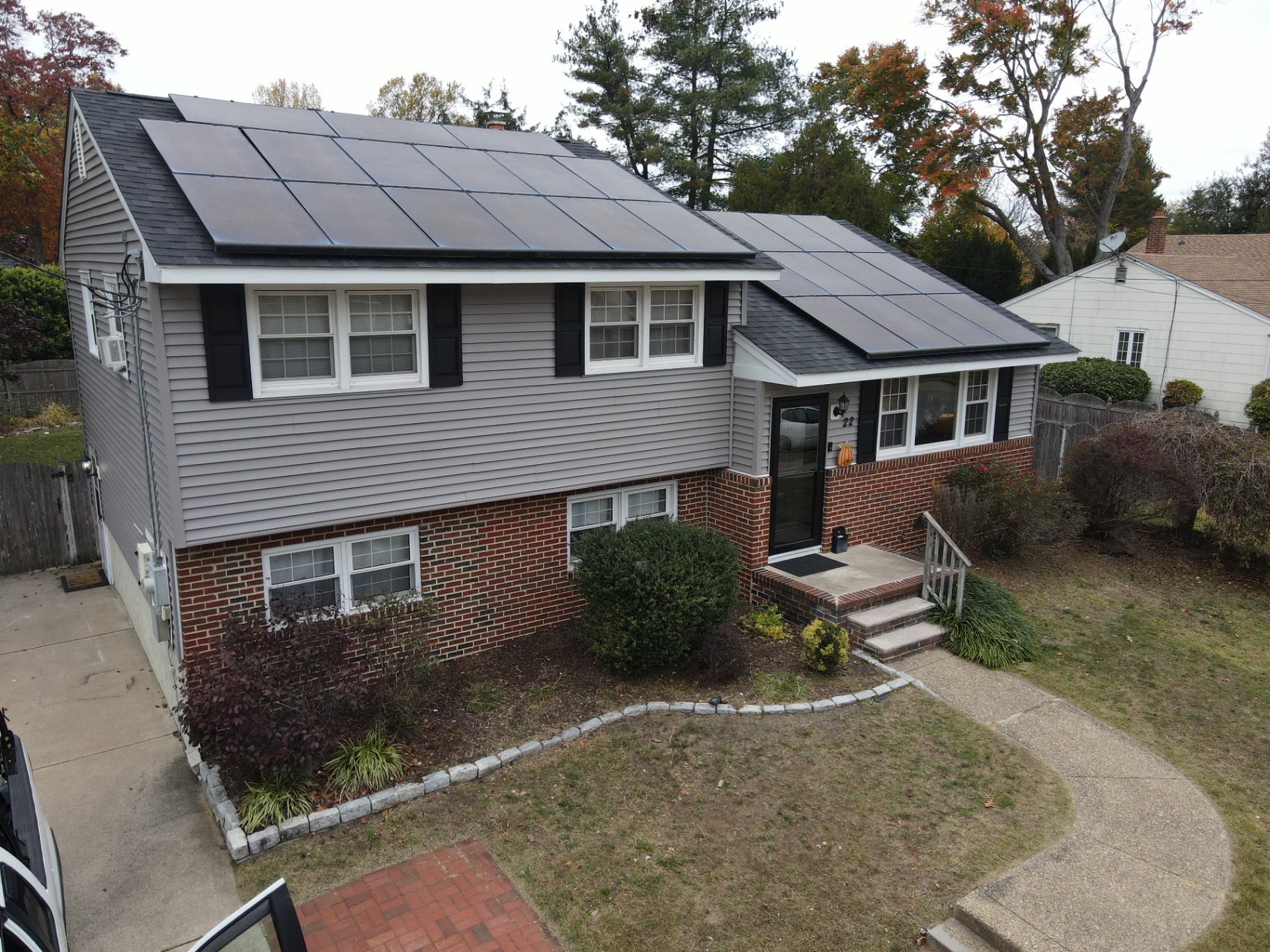 Two-story home with gray vinyl siding, brick accents and solar panels on the roof