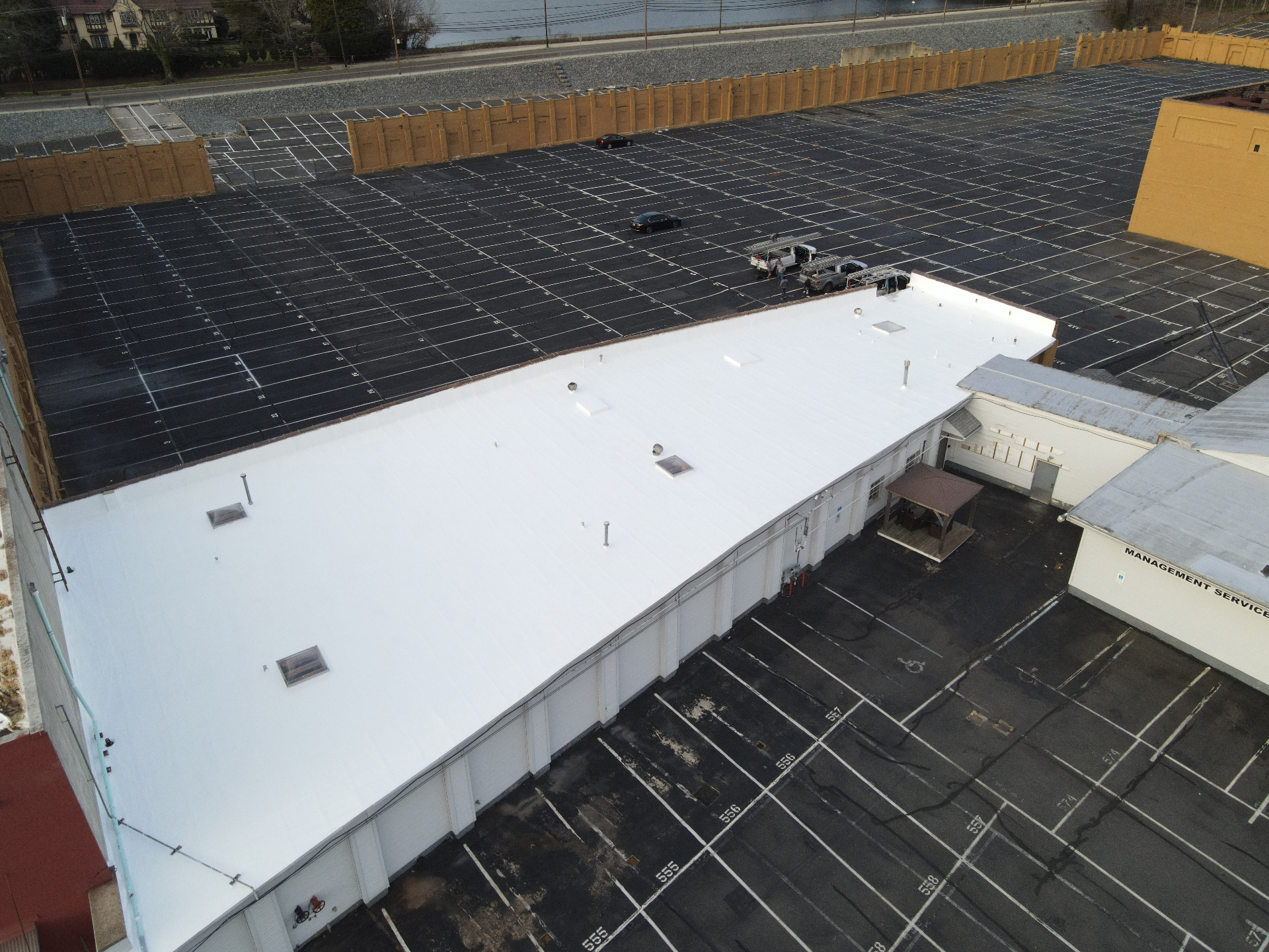 Completed white commercial roof with parking lot and adjacent structures visible