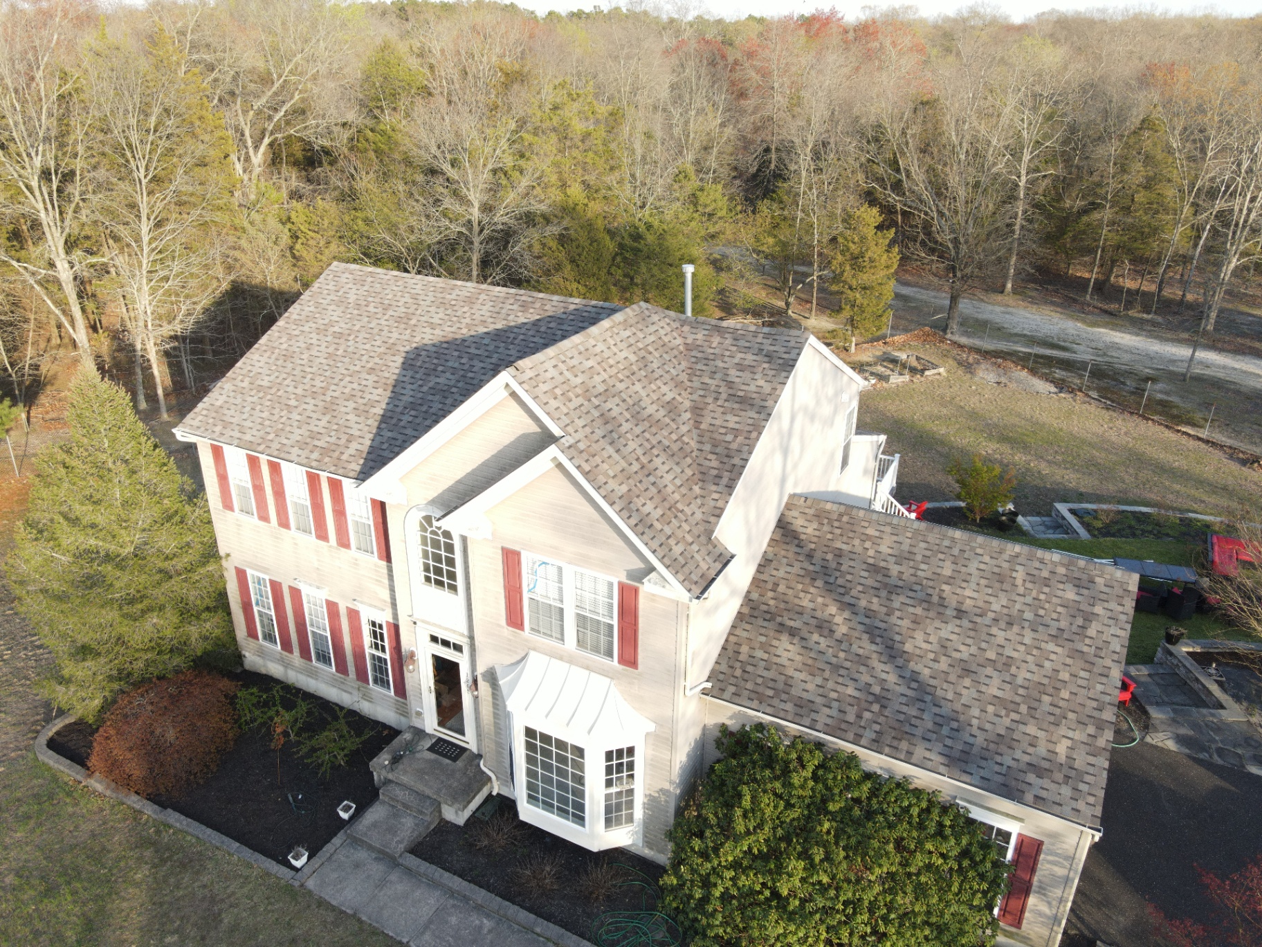 Completed residential roof on a two-story home with red shutters