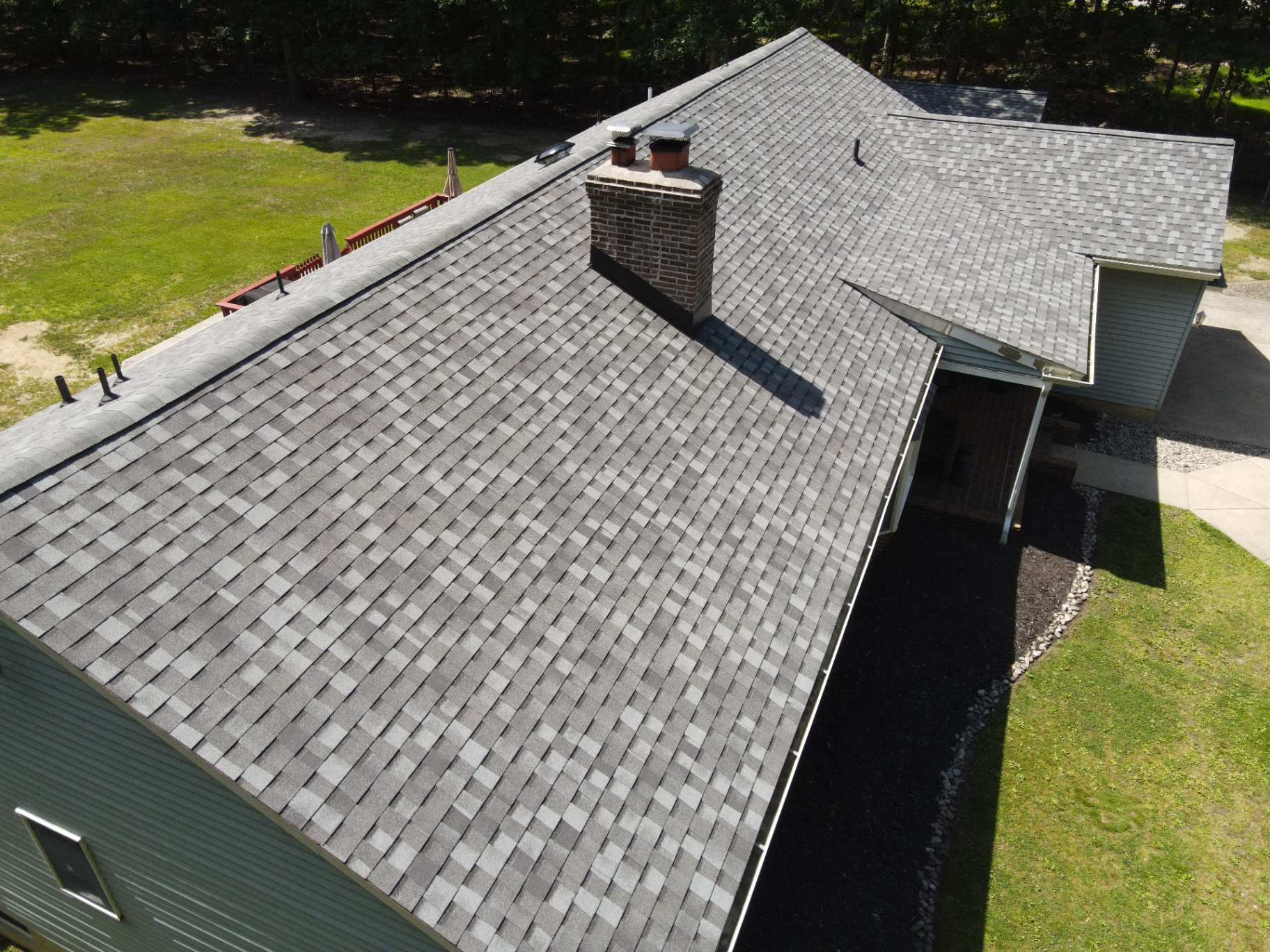 Close aerial detail of a completed gray shingle roof around the chimney and ridges