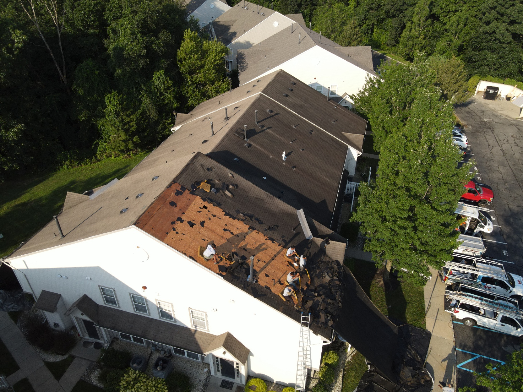 Roofing crew removing shingles from a large residential building