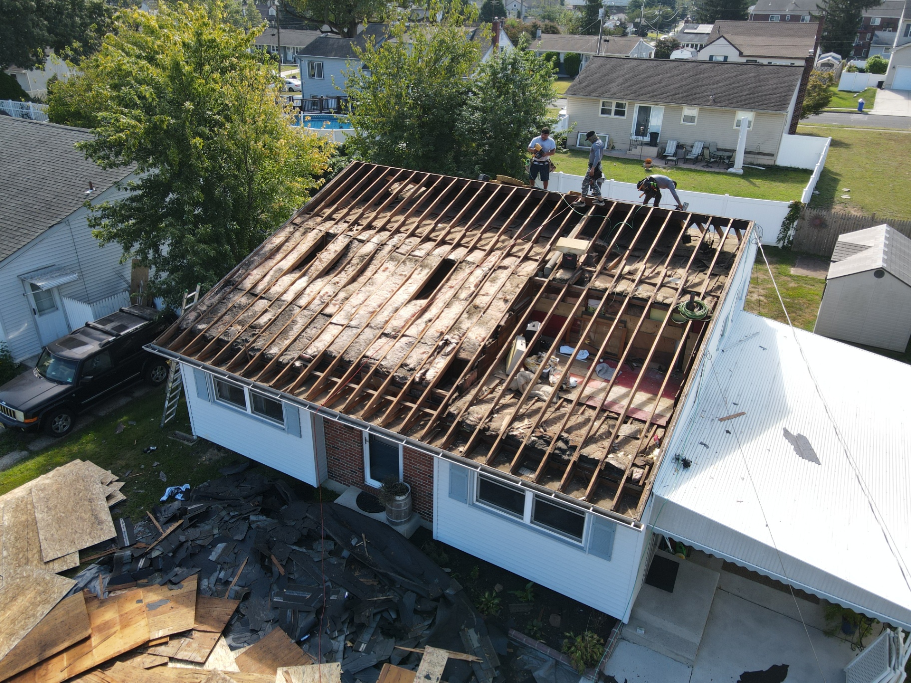 Roof tear-off in progress showing decking and crew at work