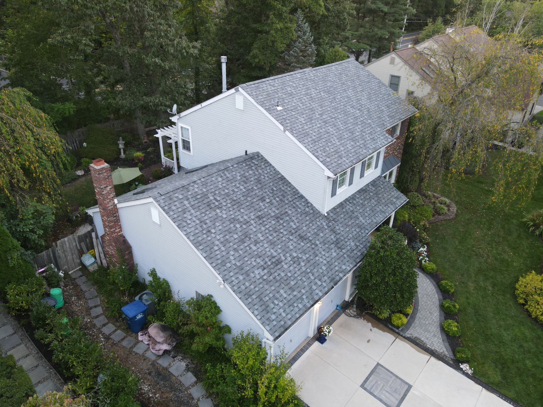 Completed gray shingle roof on a two-story home with landscaped yard