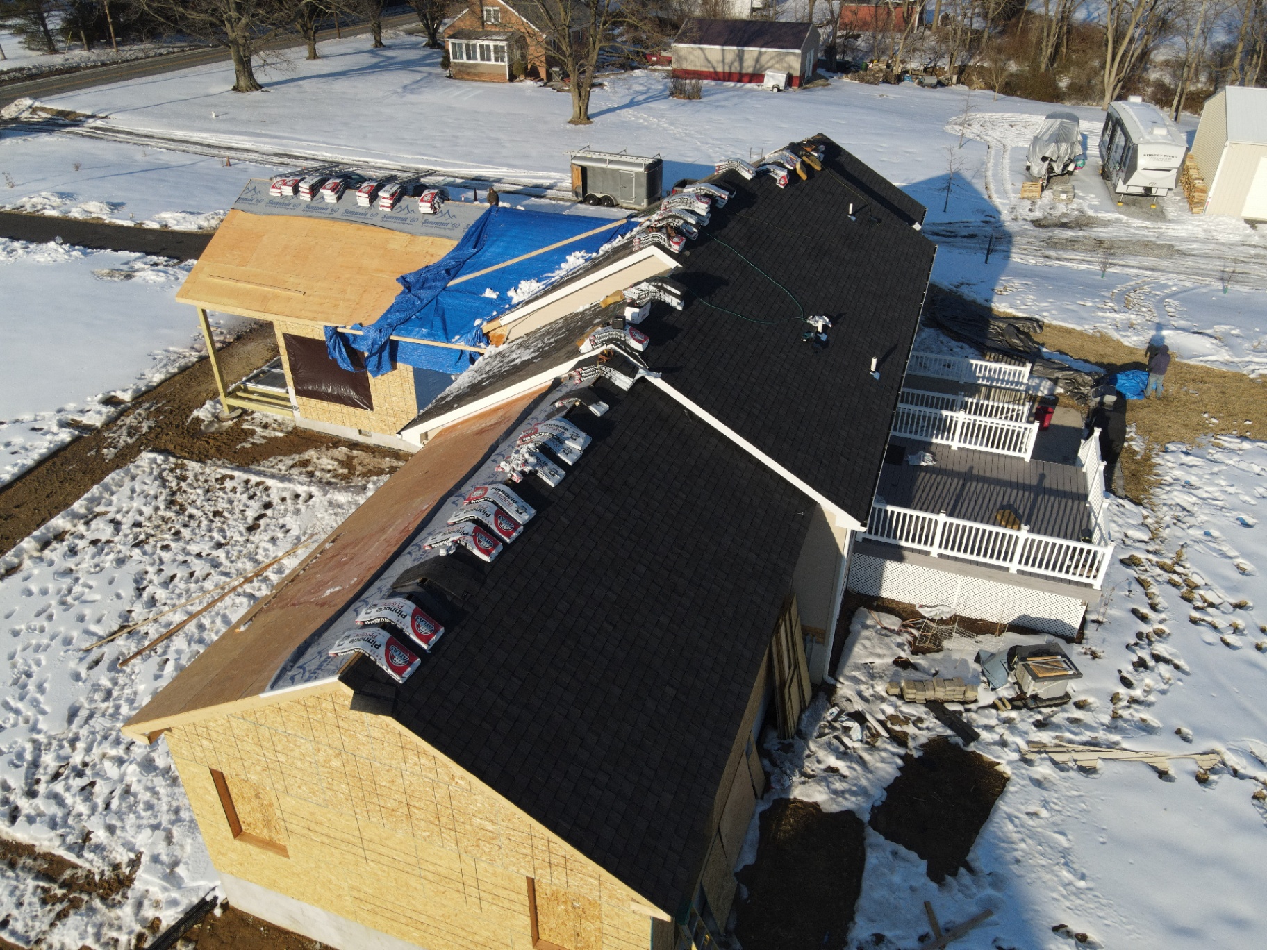Roof installation in progress during winter on a large residential addition