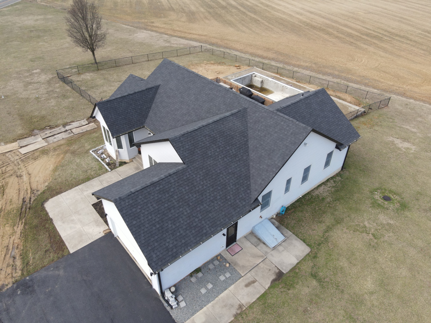 Completed black shingle roof on a large custom-built home in a rural setting