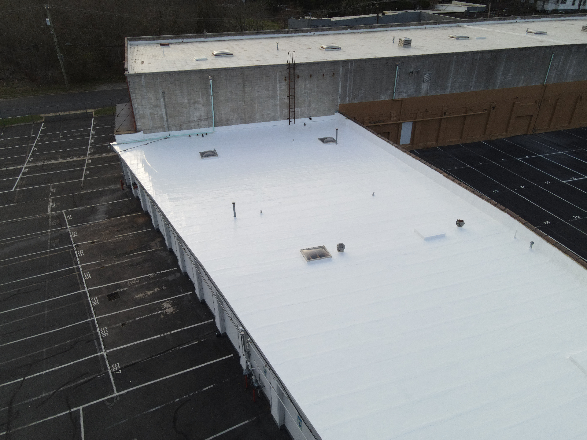 Finished white commercial flat roof viewed from one end of the building
