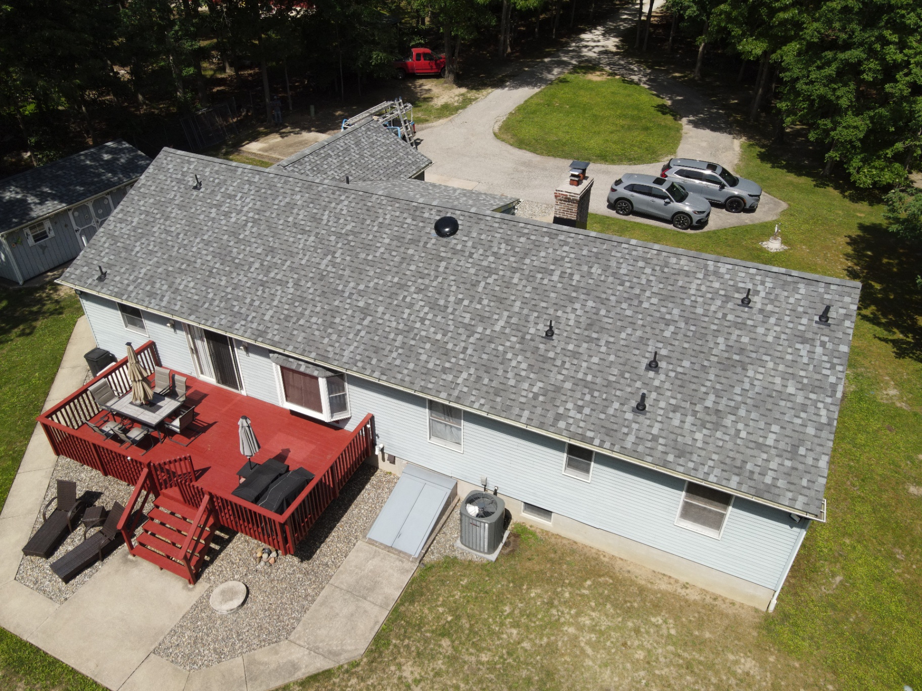 Completed gray shingle roof over a long ranch-style home and rear deck