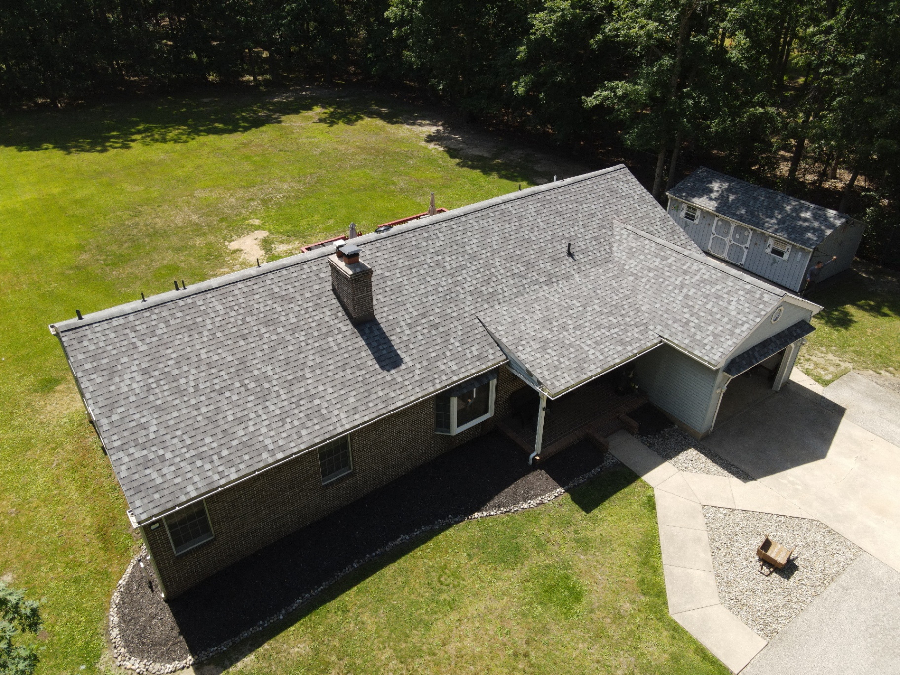 Completed gray shingle roof on a brick ranch home viewed from above
