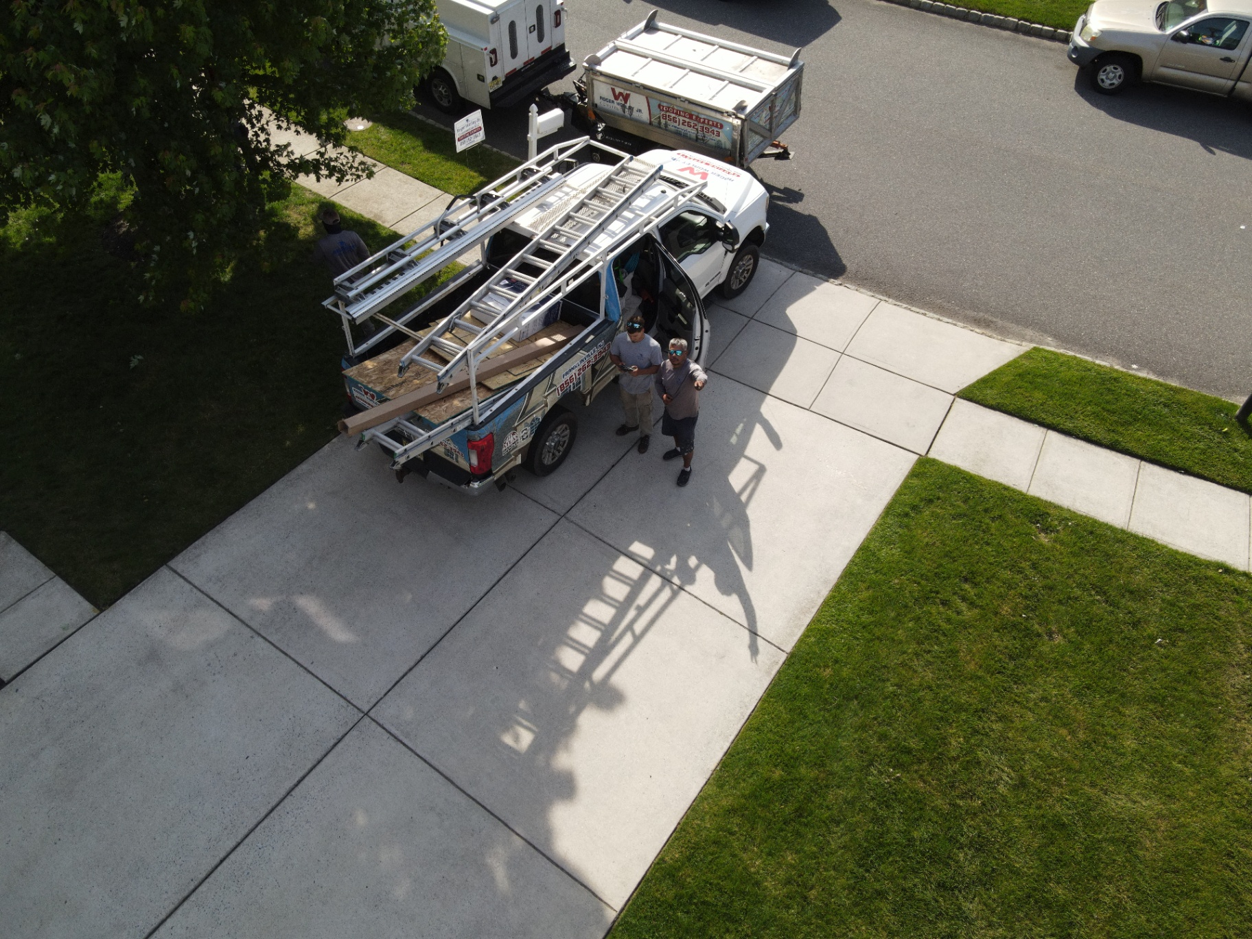Roofing crew and work trucks arriving on site before a residential roof replacement