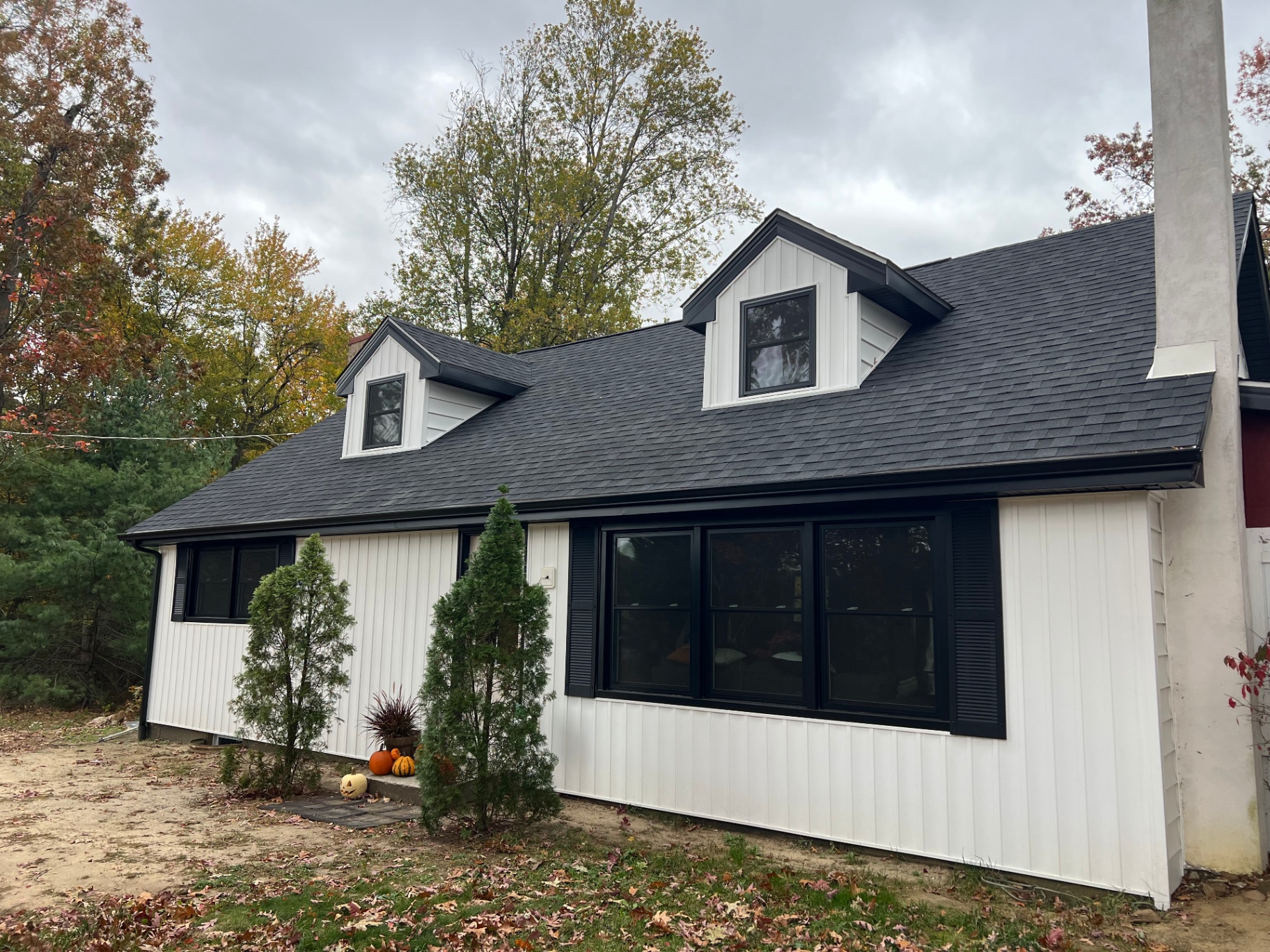 Cape Cod home with white board-and-batten and lap siding, black trim and shutters