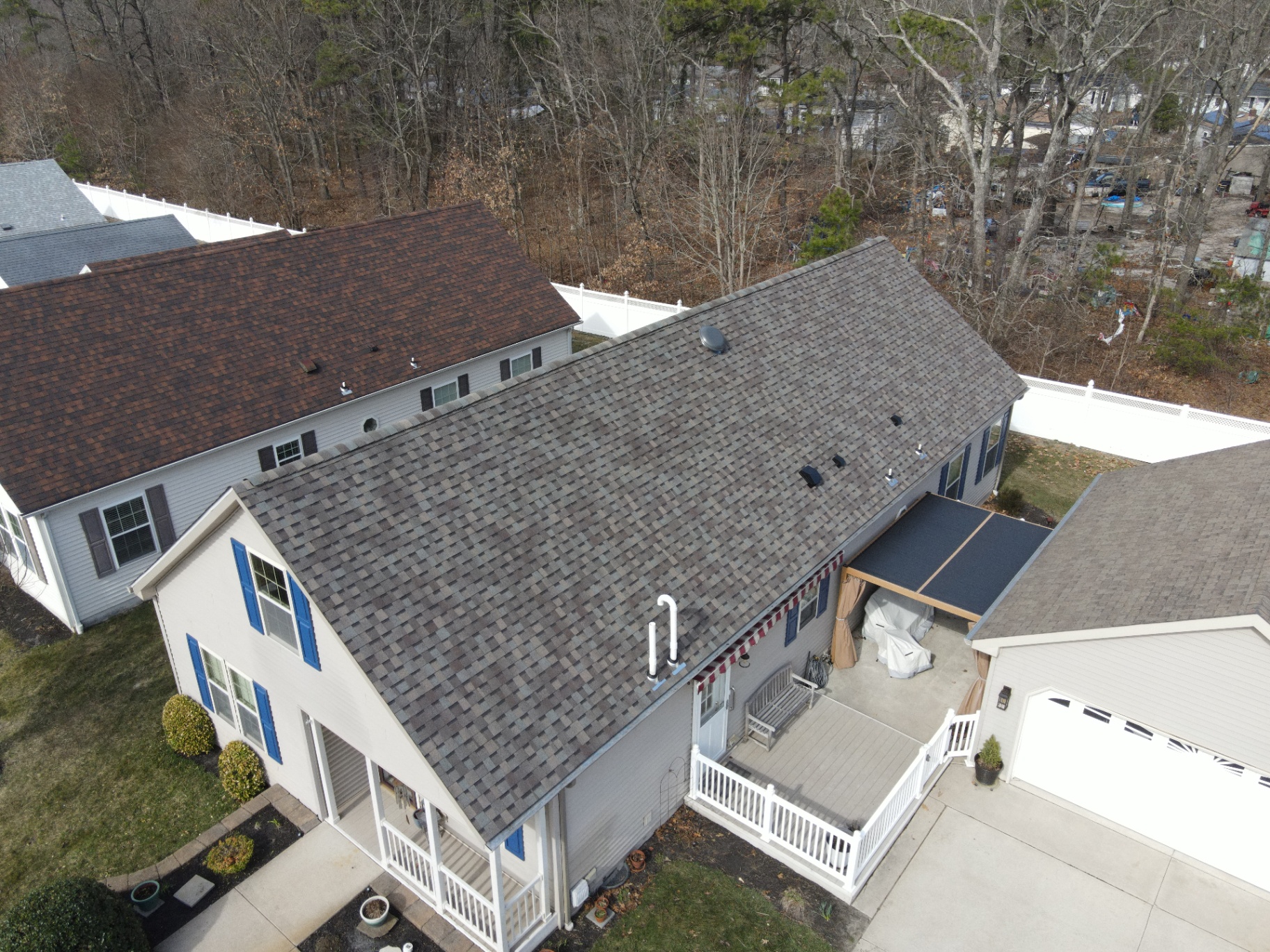 Completed multi-tone shingle roof on a two-story home with blue shutters