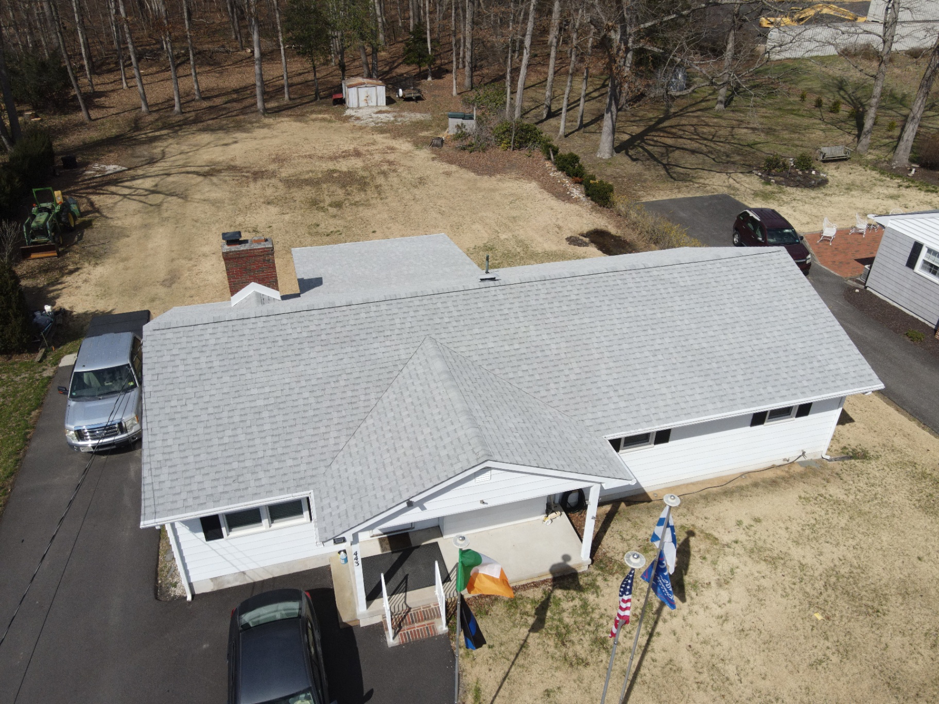 Completed light-gray shingle roof on a ranch home in a wooded lot