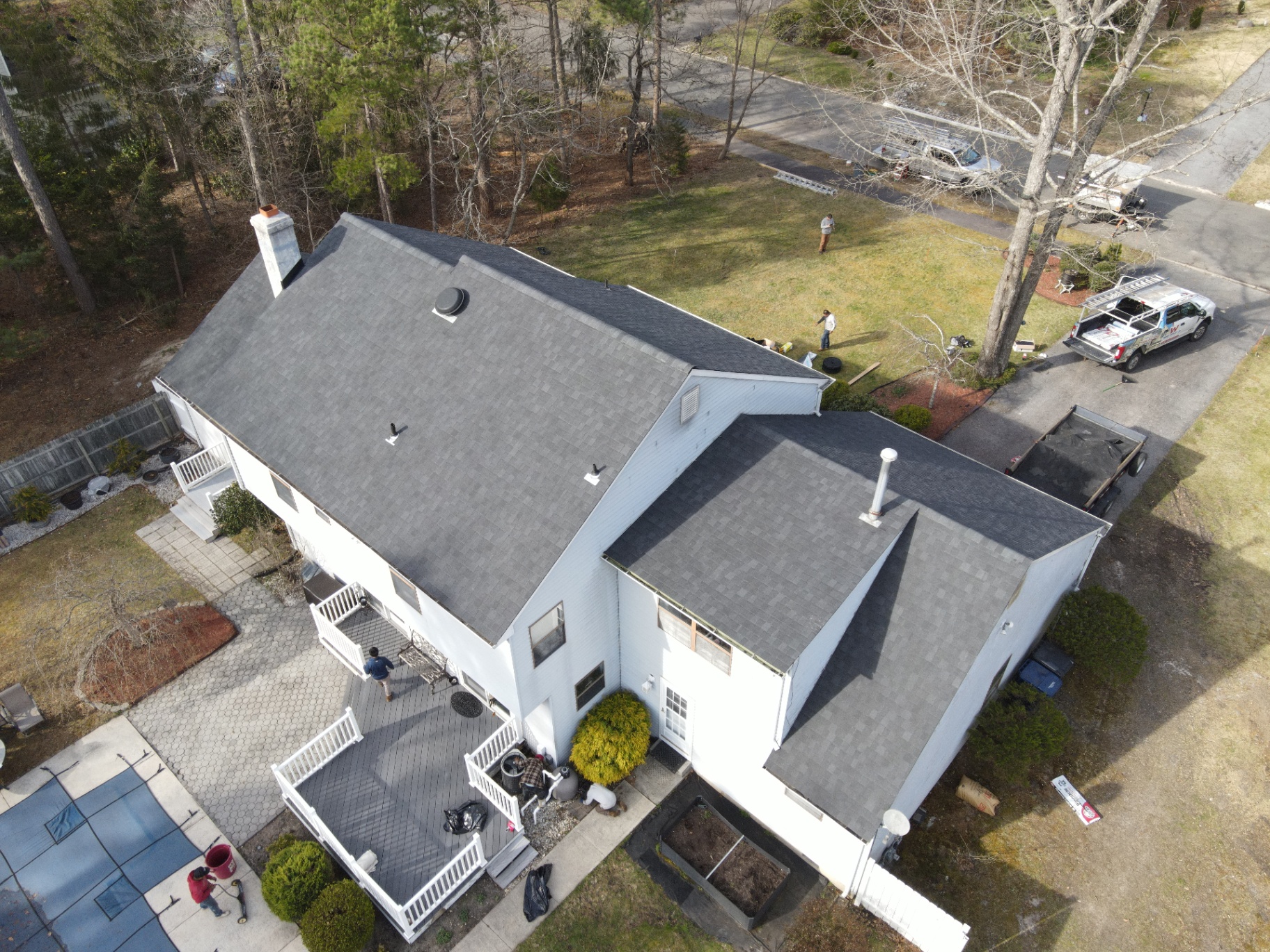 Completed charcoal shingle roof on a two-story home with crew on site